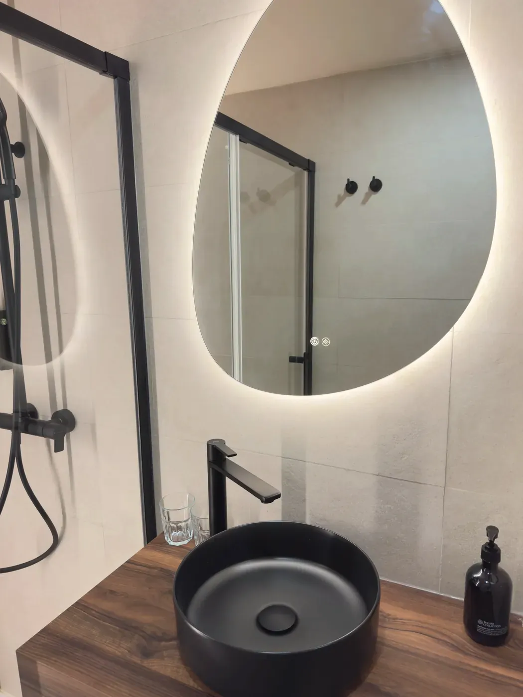 Lavabo negro sobre encimera de madera y espejo con luz