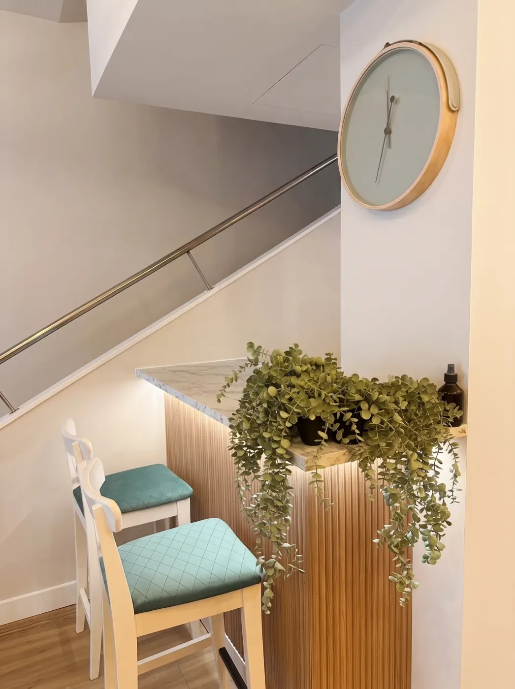 Escalera de acceso con reloj y planta en la recepción del hotel