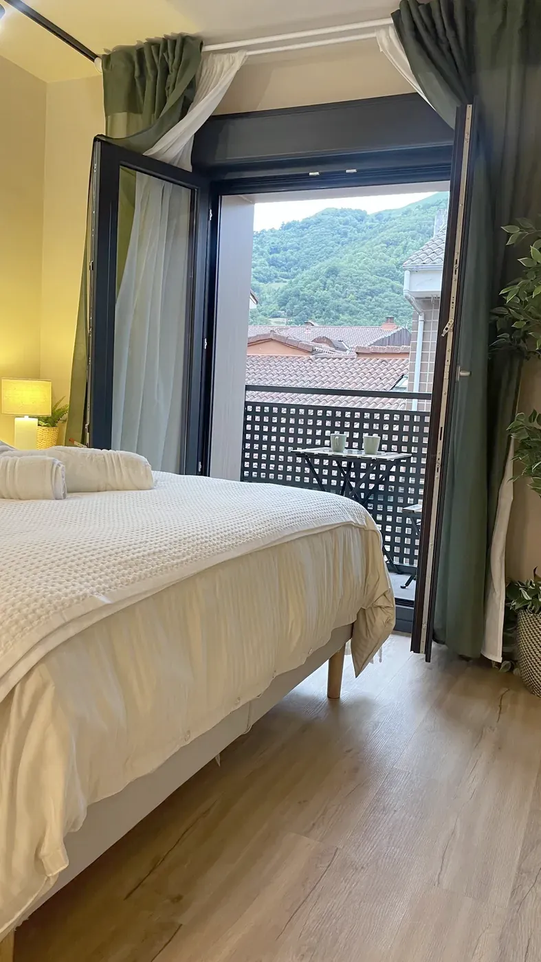 Cama de la suite con el balcón abierto y vistas al monte