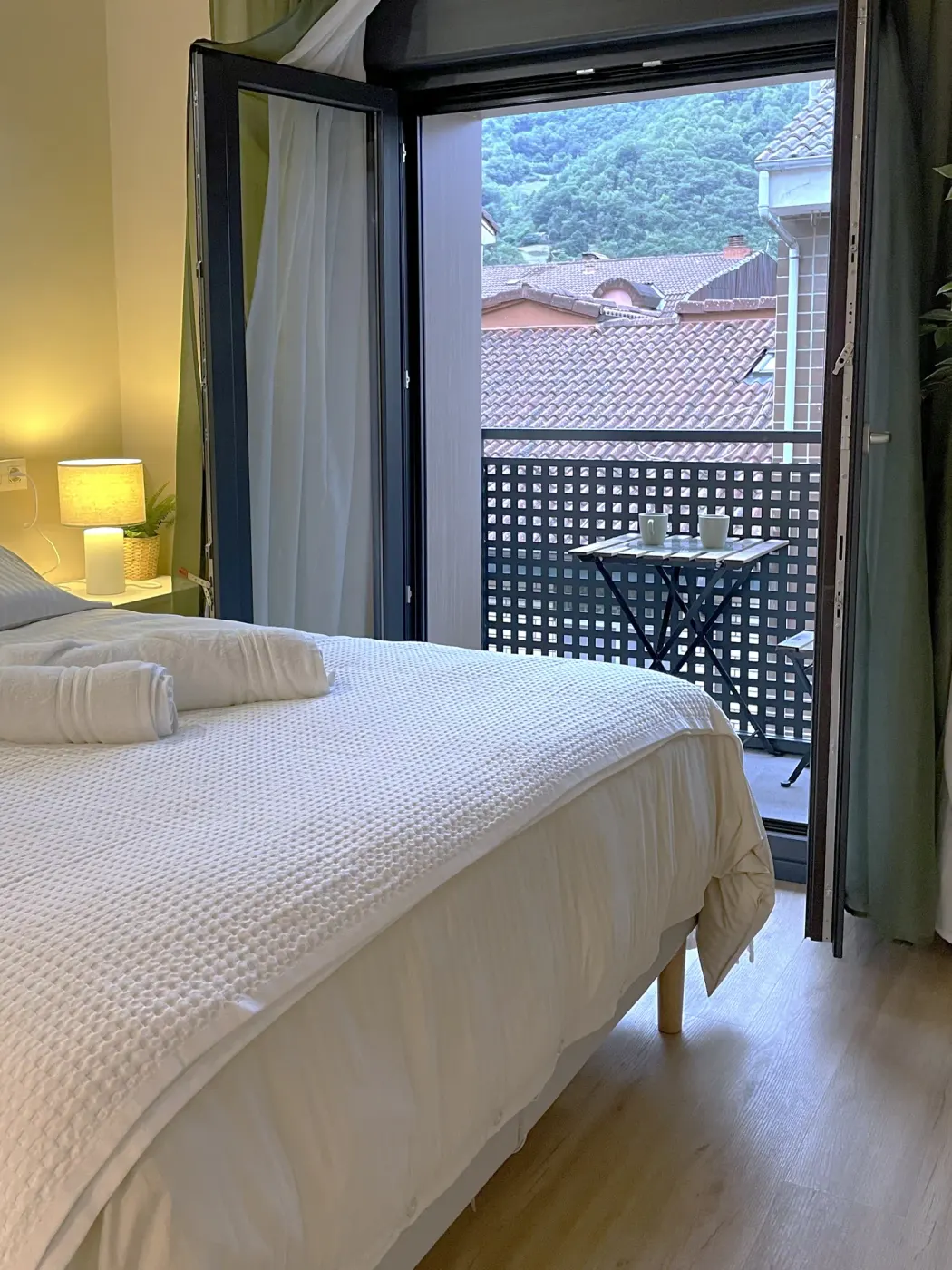Cama de la suite con el balcón abierto y vistas al monte